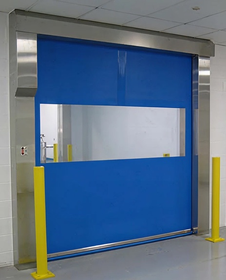 Blue high speed fabric roll-up door with vision window and stainless steel frame, yellow guard posts on each side
